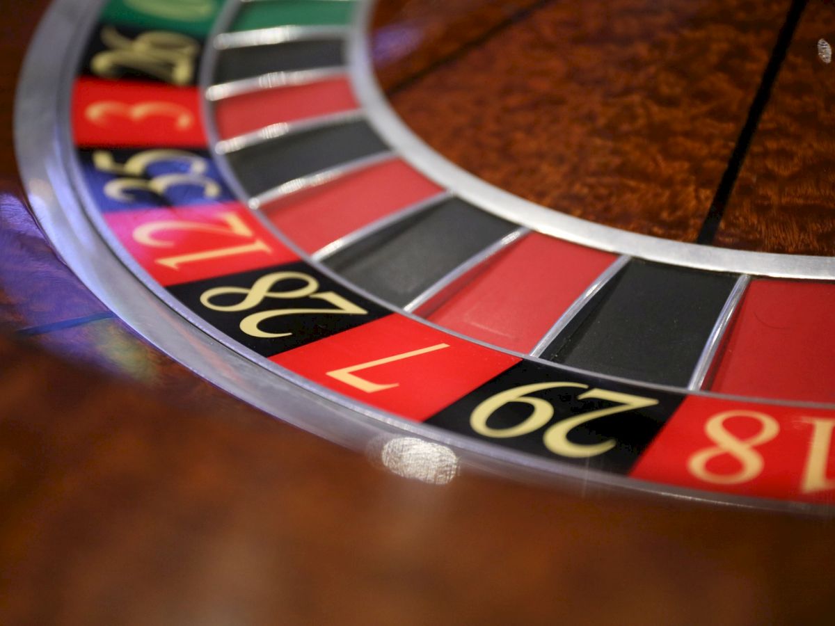 The image shows a close-up of a roulette wheel, featuring red, black, and green numbered slots, typically found in a casino setting.
